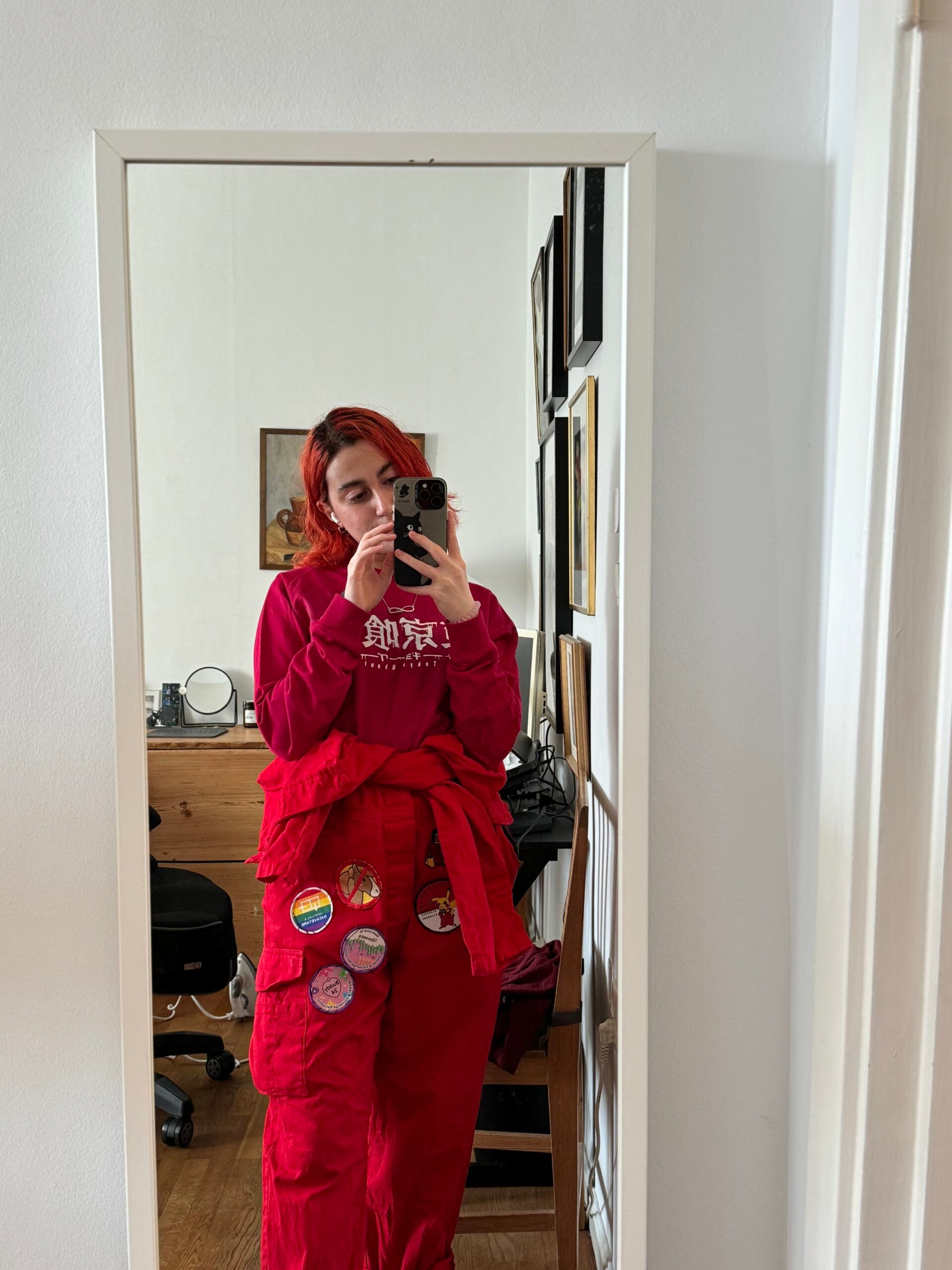 A mirror selfie of a girl in her red overall