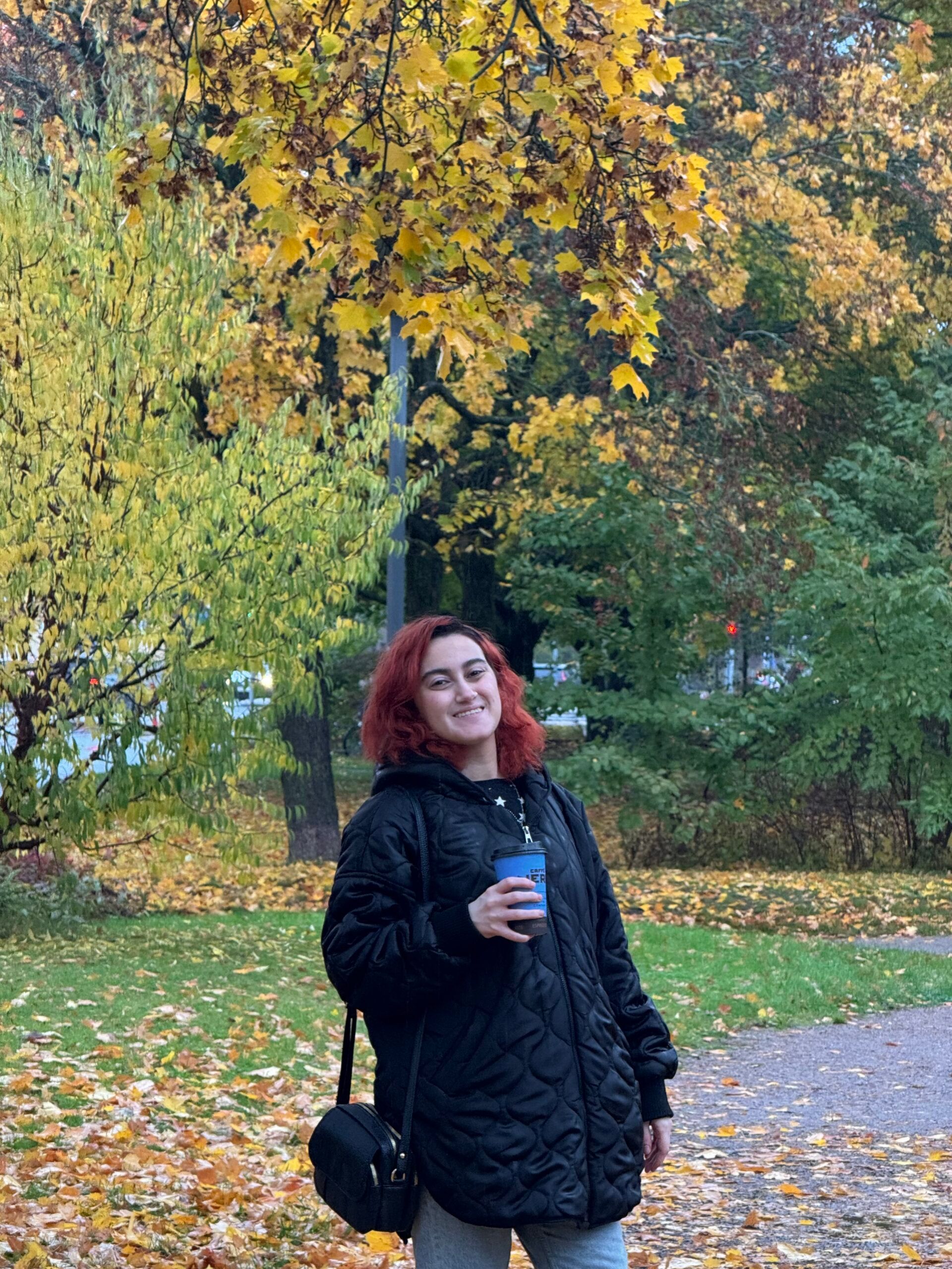 A girl in a park holding a cup of coffee