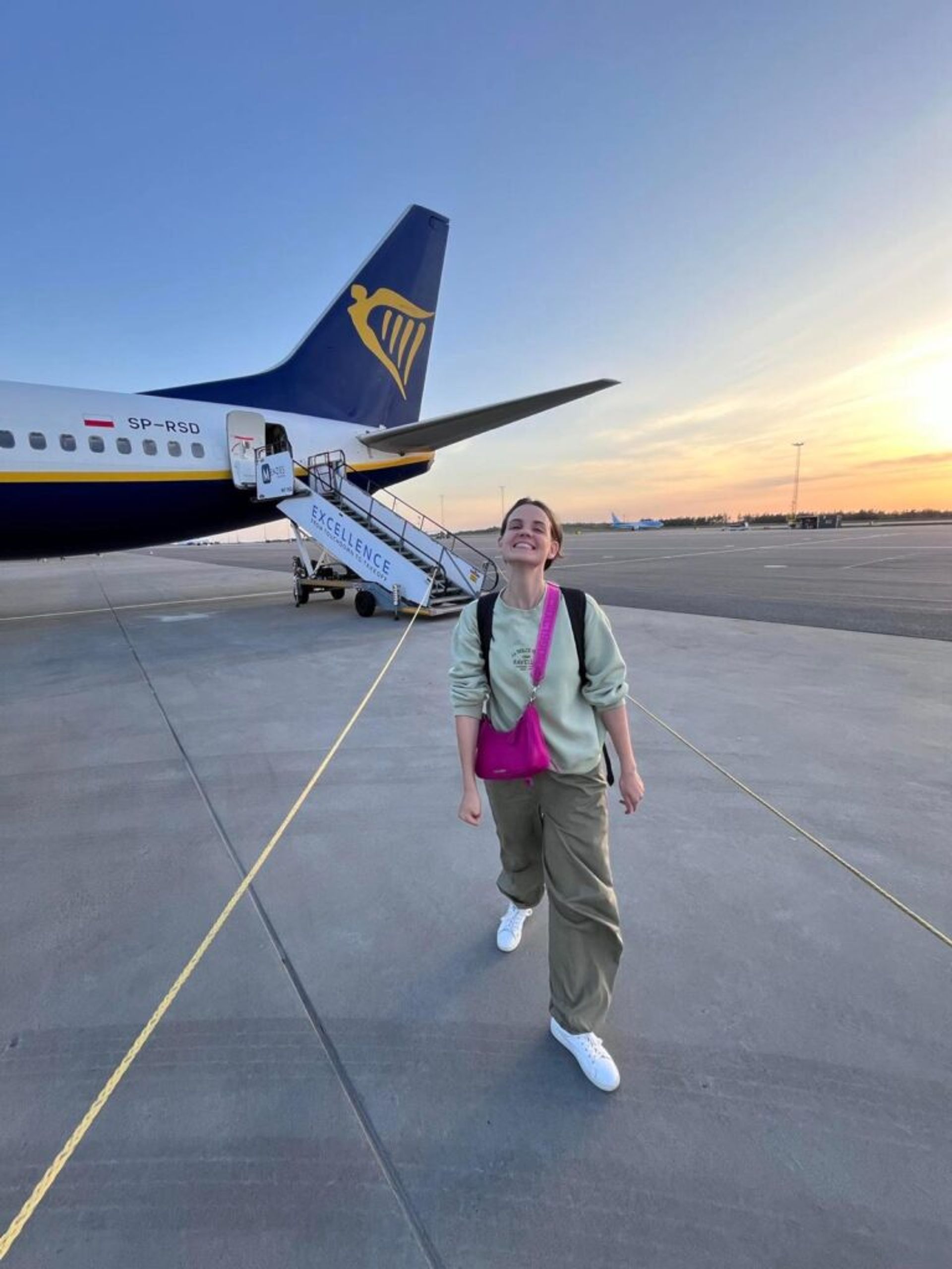 A girl posing in front of a plane.