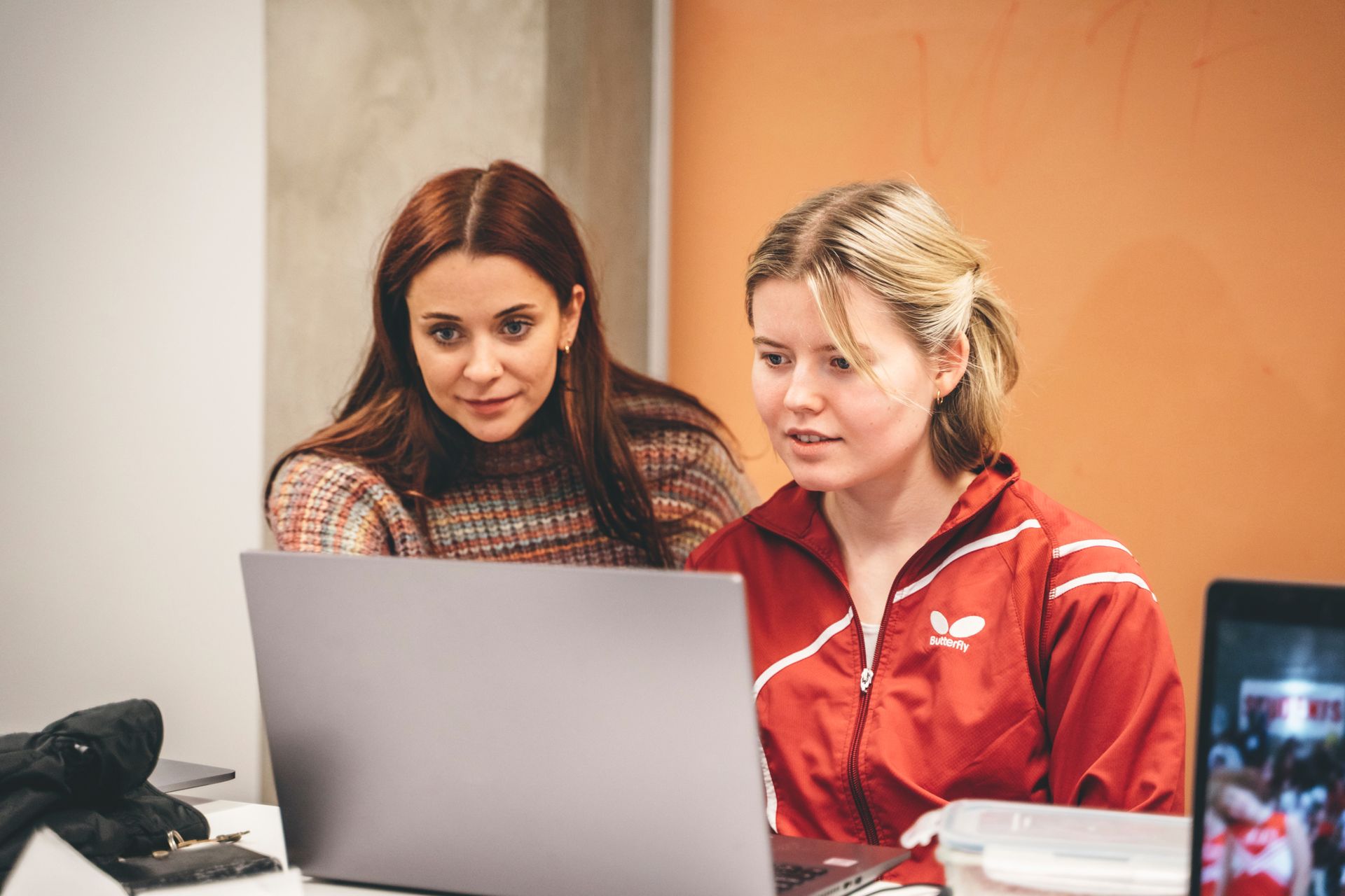 Two young women look at a computer screen.