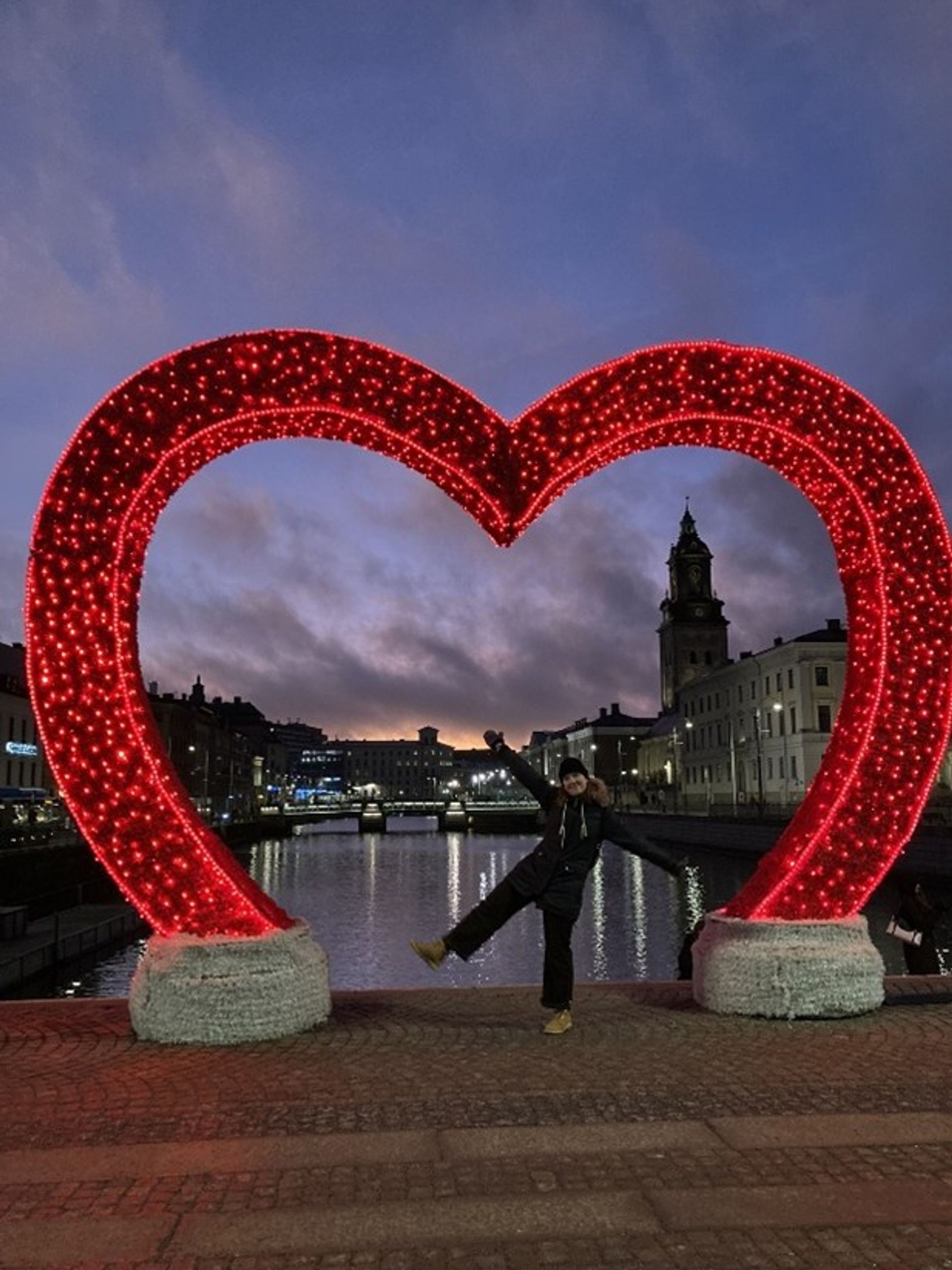 Heart-shaped decoration in Gothenburg and a girl posing in front. 