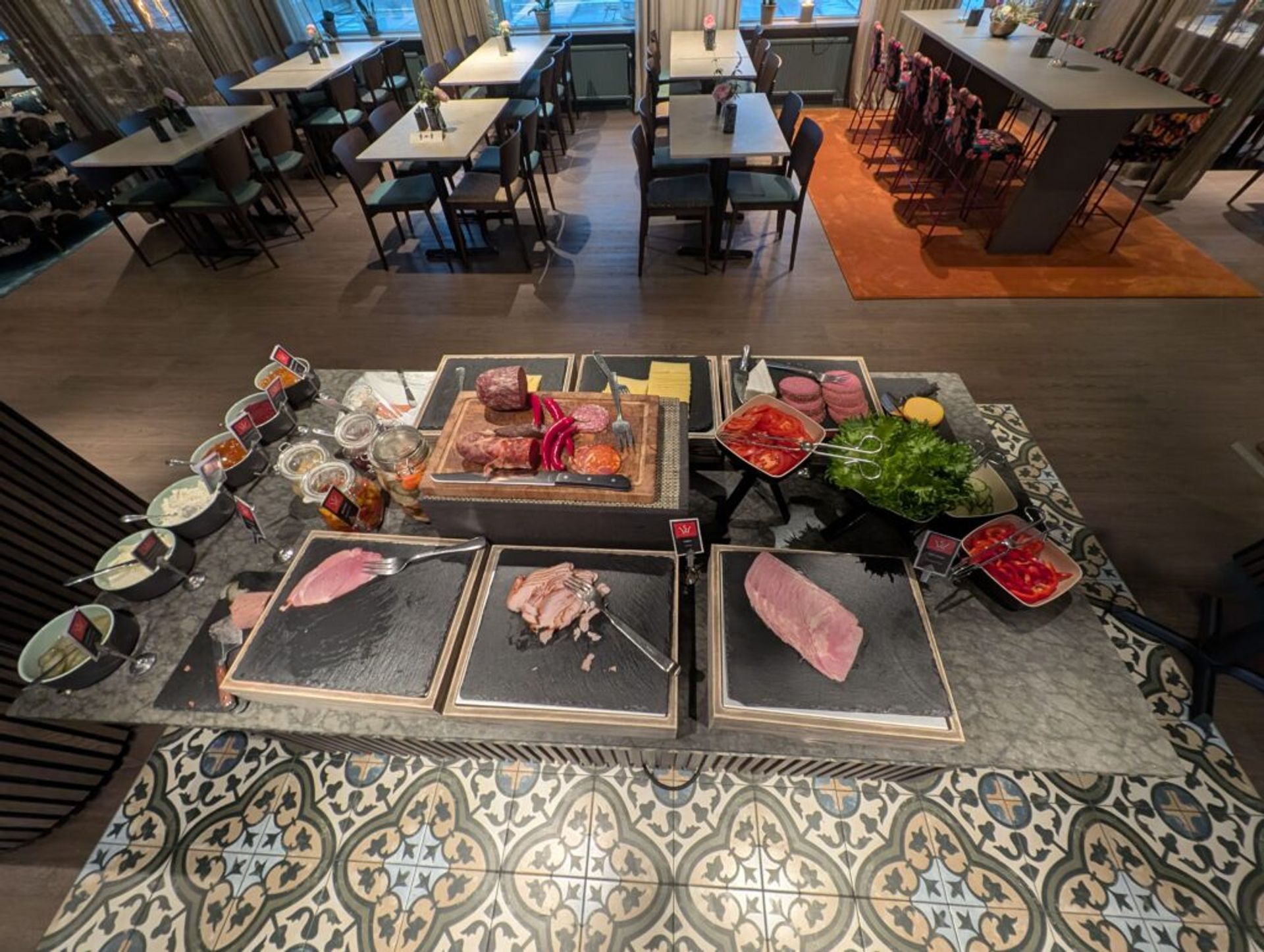 A breakfast buffet in Sweden. On the table there is a variety of cold meats, cheeses and vegetables. 