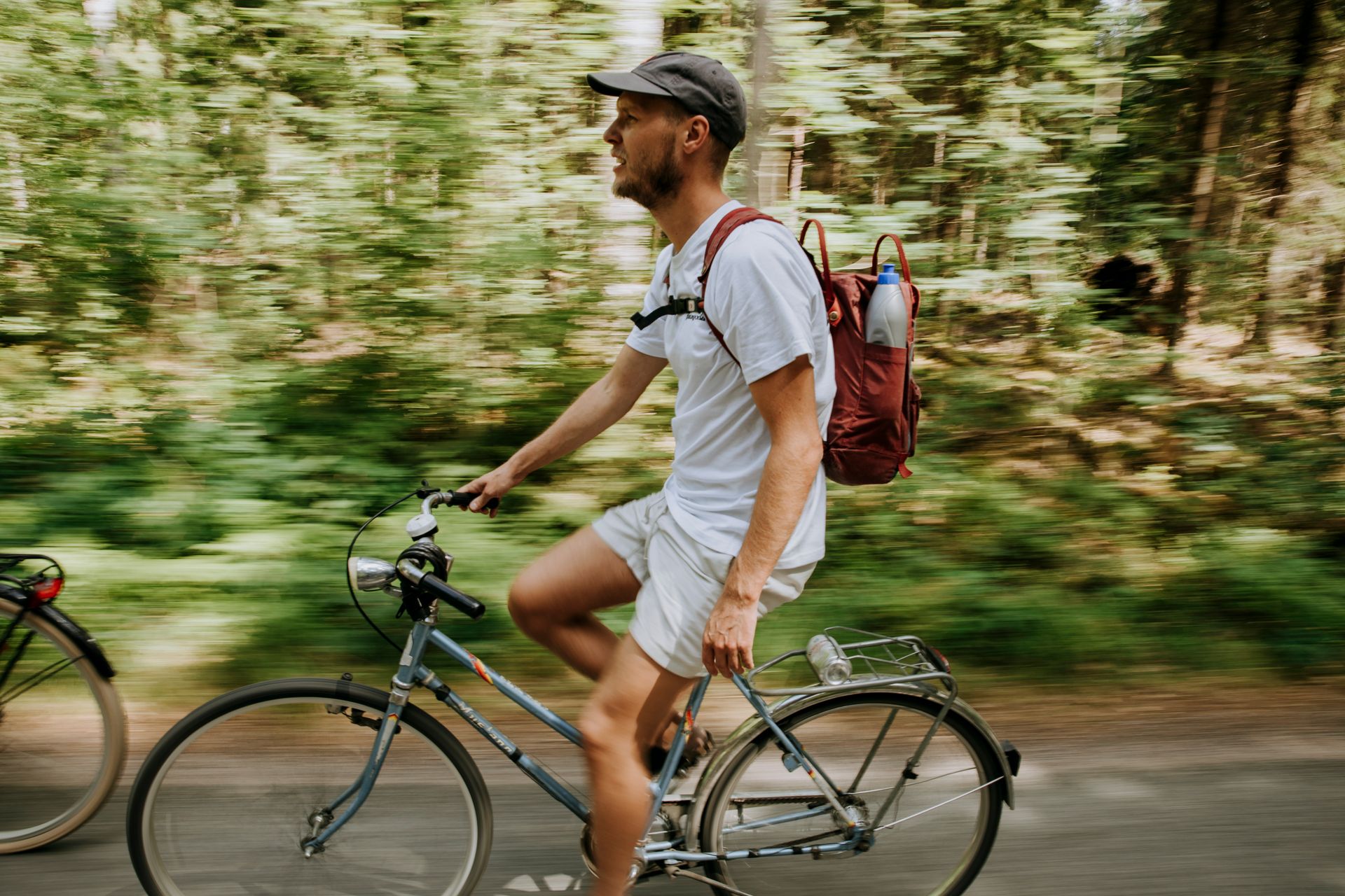 A man dressed in T-shirt and shorts on a bike in a leafy forest.