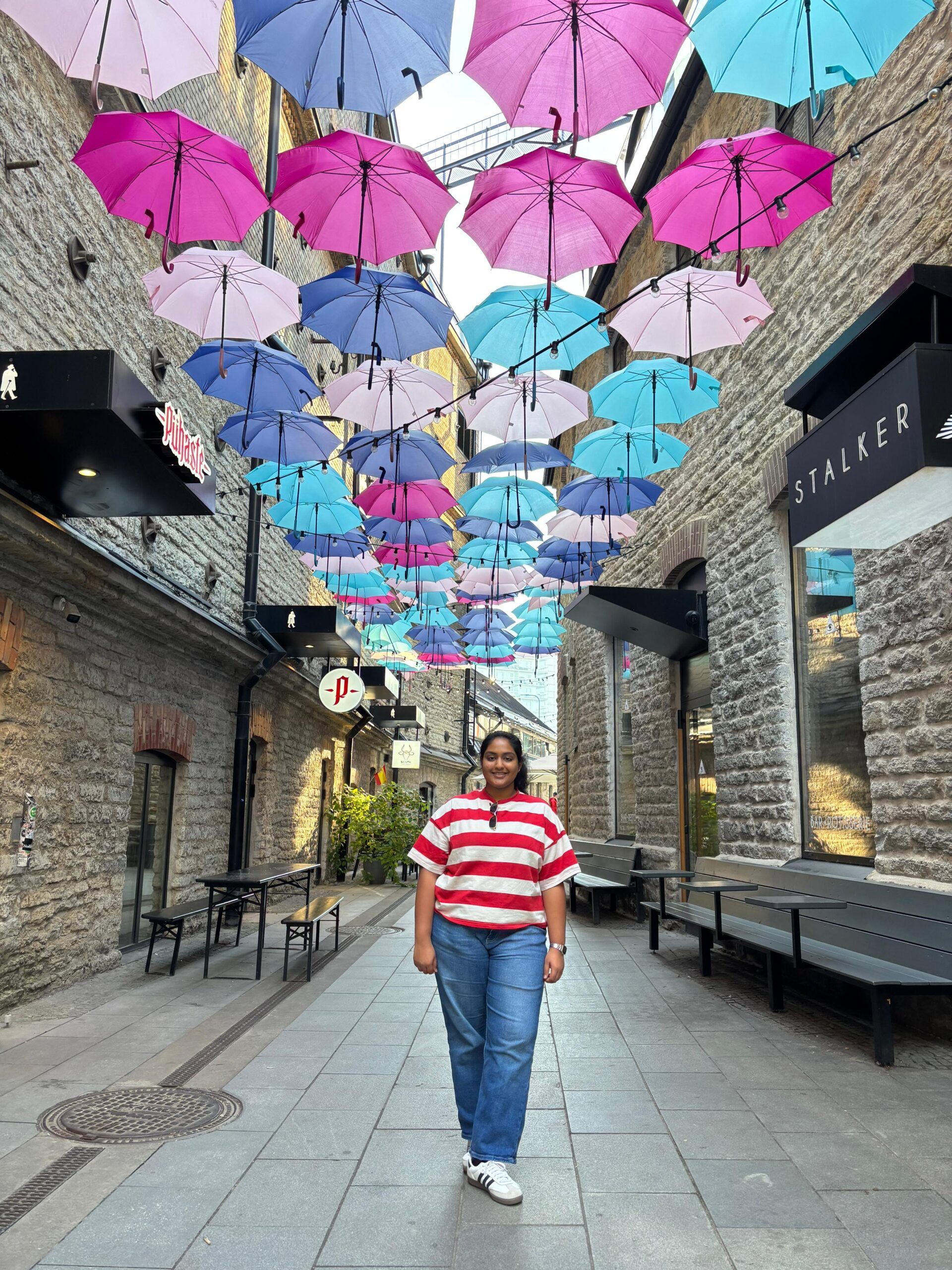 A girl under a pathway of colored umbrellas