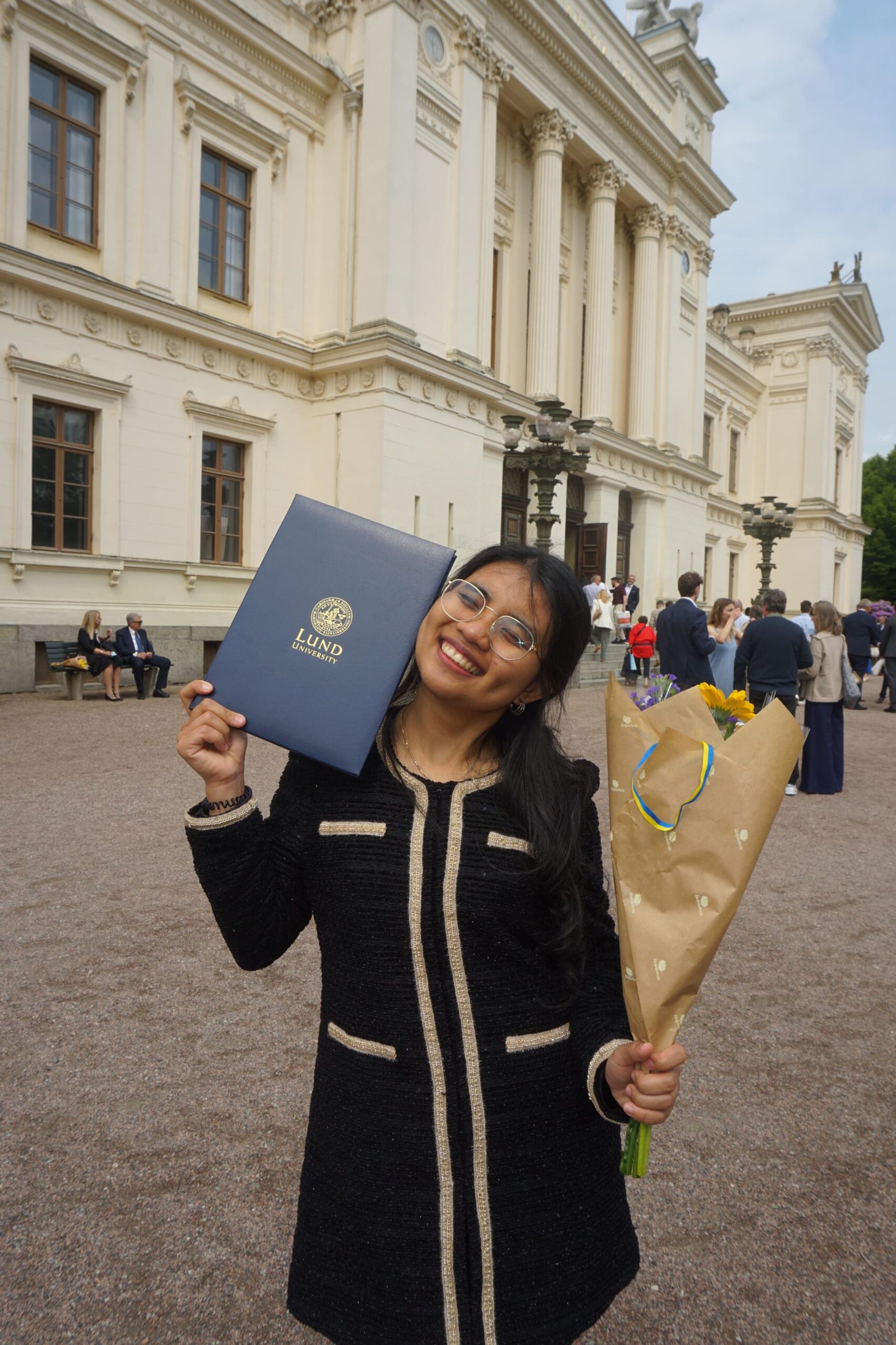 A girl posing with flowers and diploma. 
