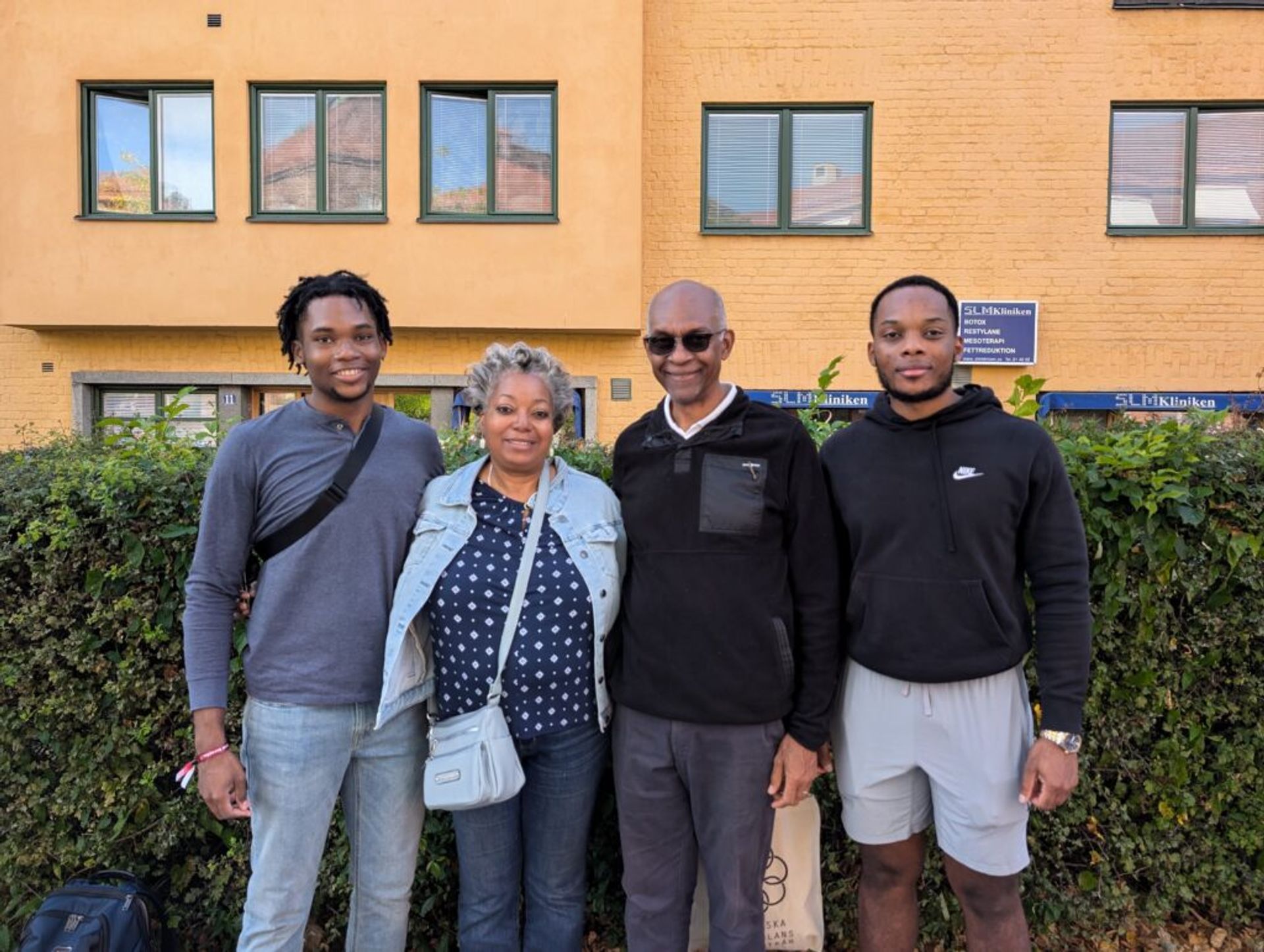 Joshua and his mother, father and brother posing for a picture in front of a yellow building in Stockholm.
