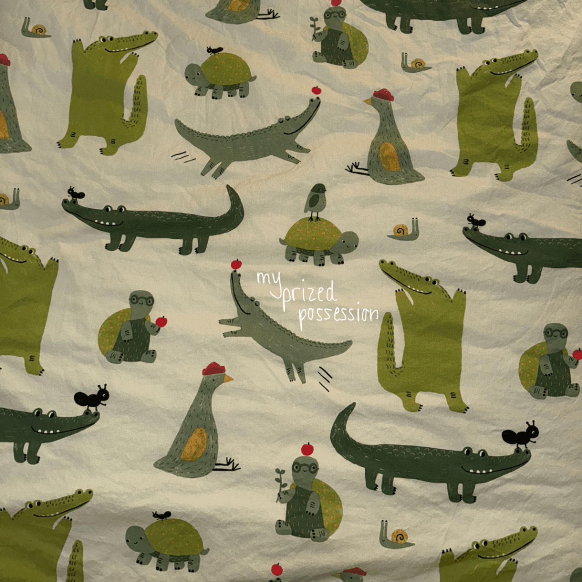 A photo of a duvet cover with green alligators, snails, turtles, and birds.