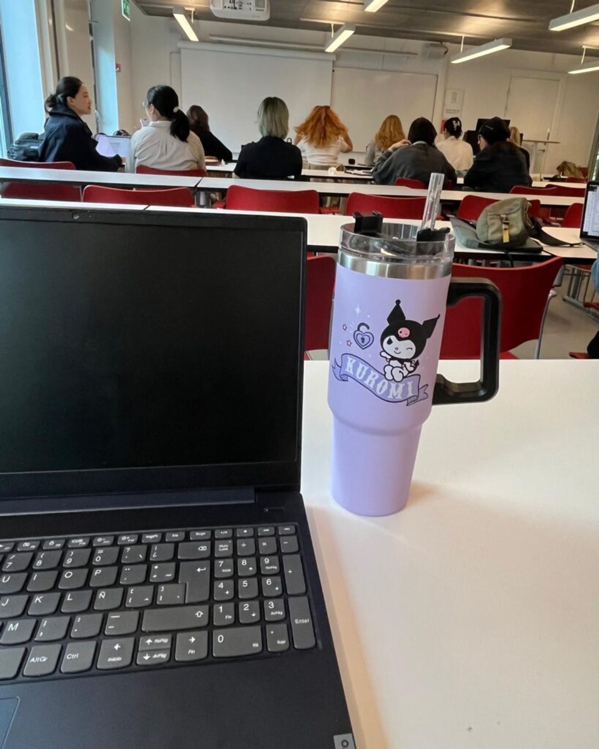 A computer and a standley cup of someone listening to a class