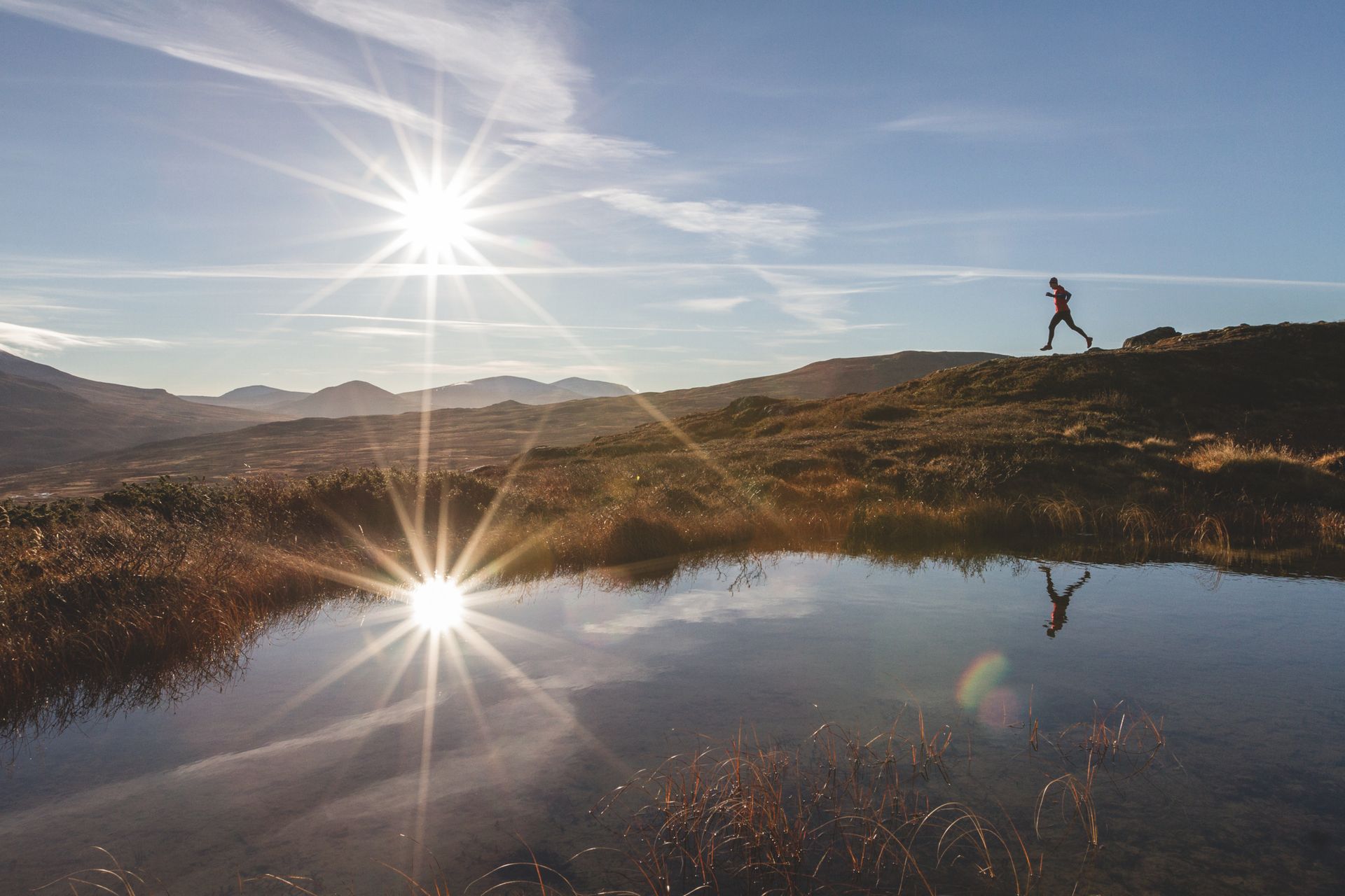 A single runner out in nature with the gleaming sun as a backdrop