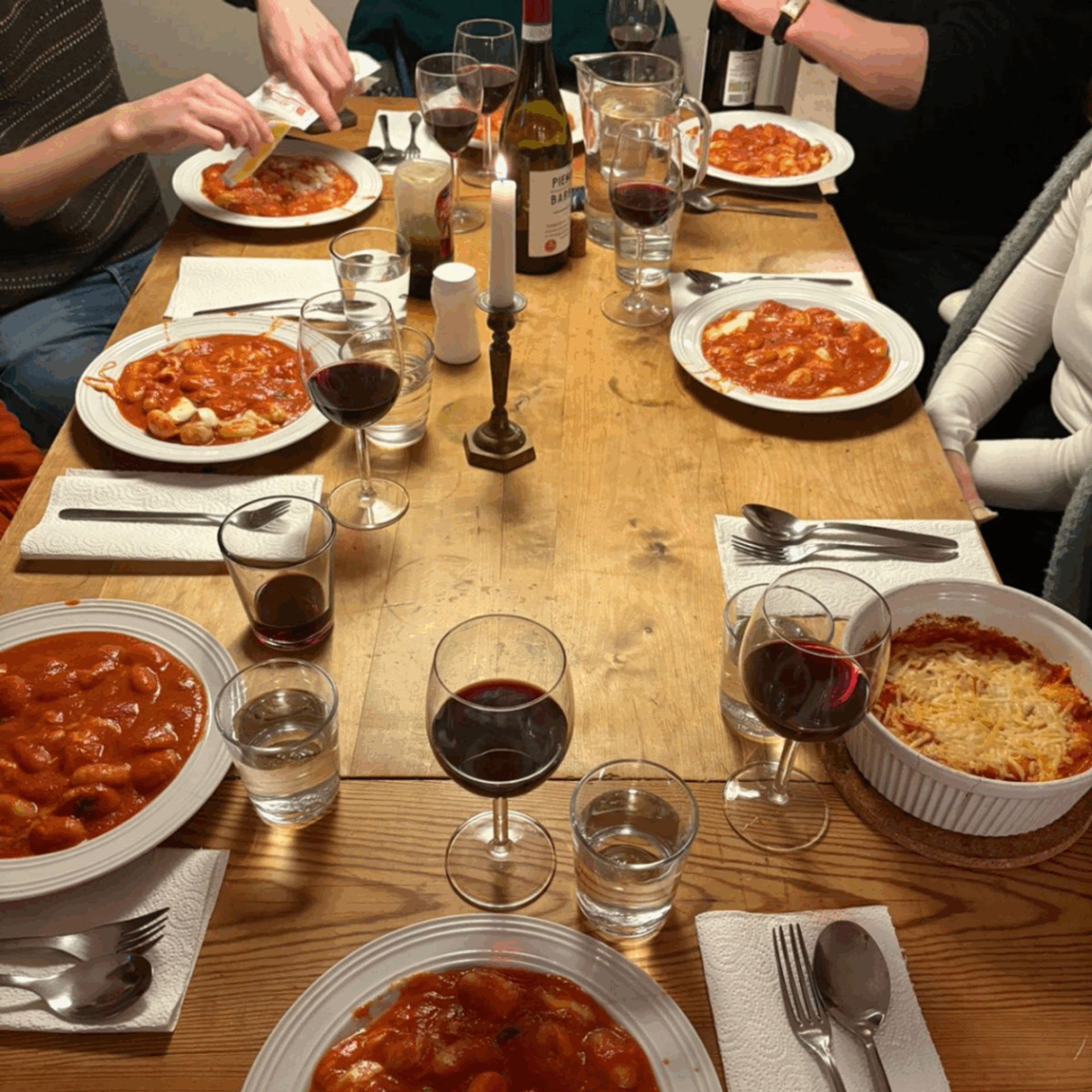 A photo of a dinner with my friends-- a gnocchi pasta with red sauce and red wine