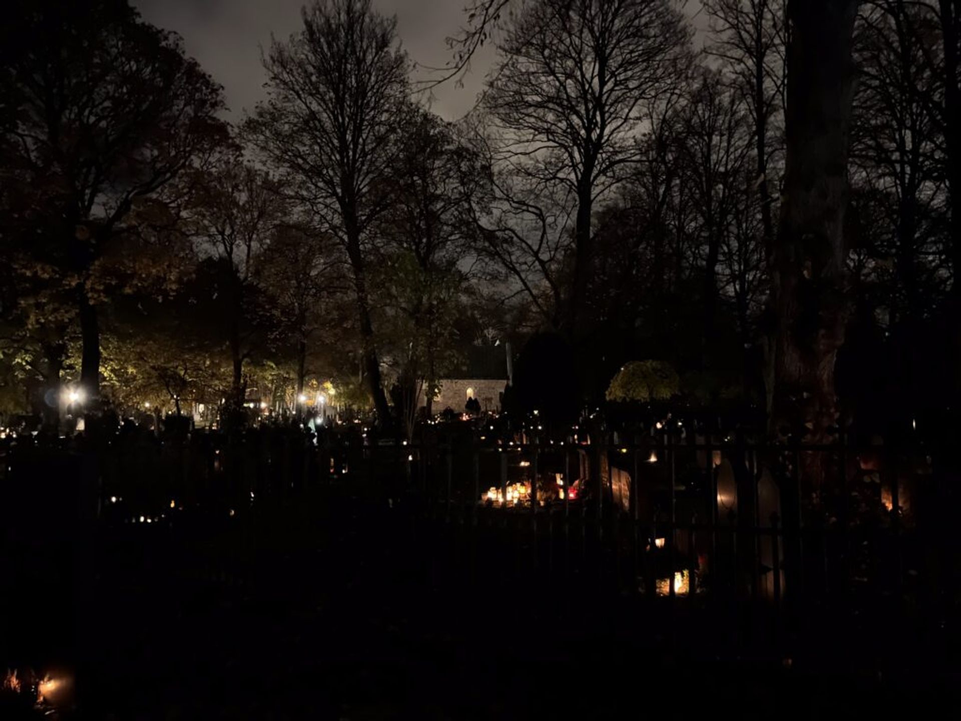 Many candle-lit graves in front of a small church.