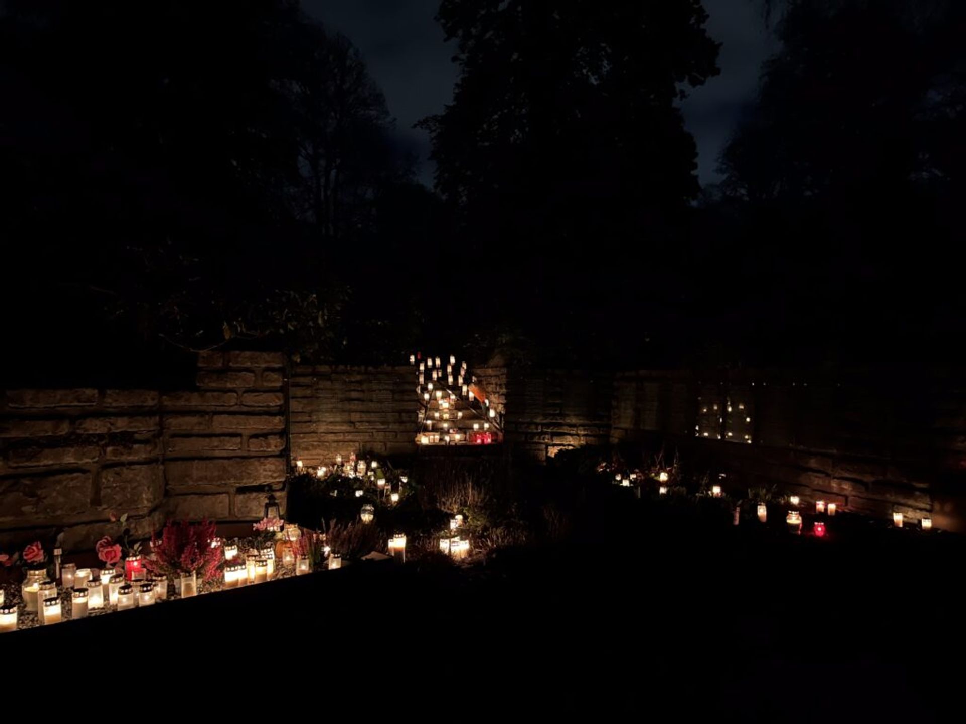 A stone wall and stairs, full of candlelights.