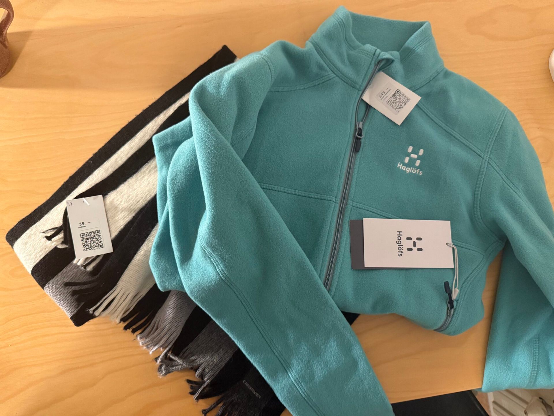 A photo of a black, white, and grey striped scarf and a blue fleece Haglöfs zip up that I got from the thrift store.