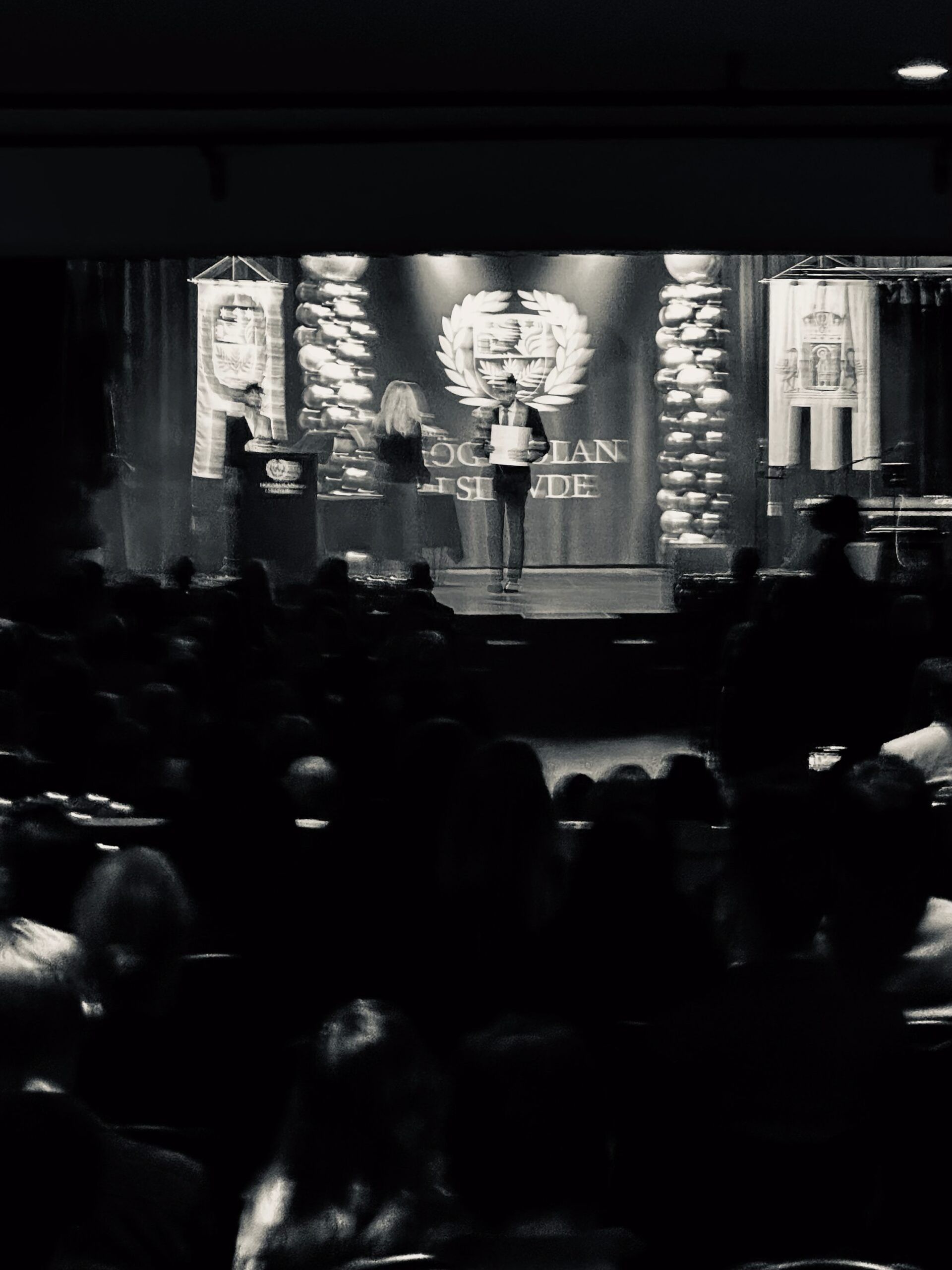 a moody photo of a student accepting their diploma in monochrome