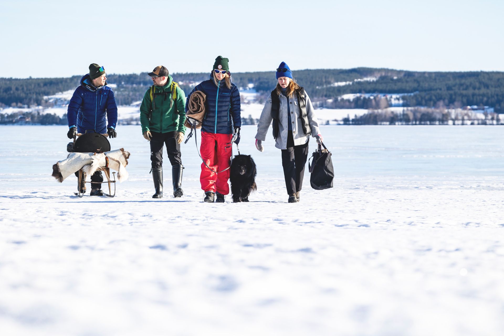 A group with a dog walking across an ice-covered lake.